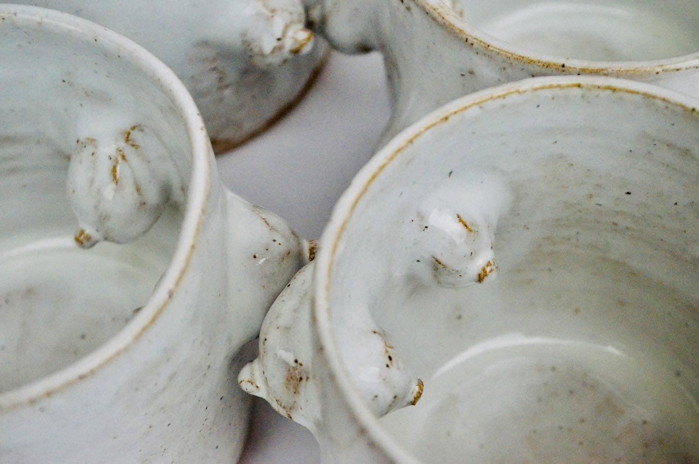 Cups with sculpted forms, stacked and glazed in white