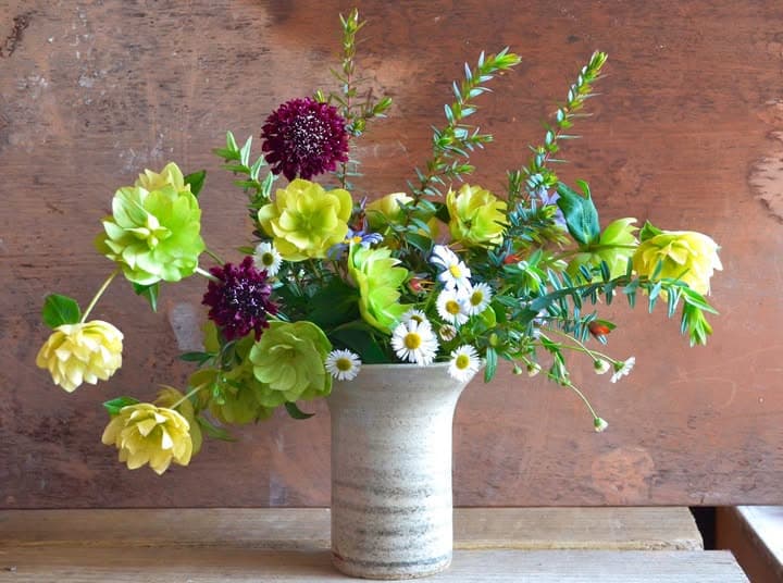 A pale stoneware vase holding spring flowers