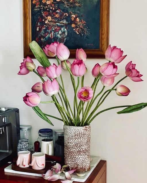 A beaded vase holding pink lotus stems